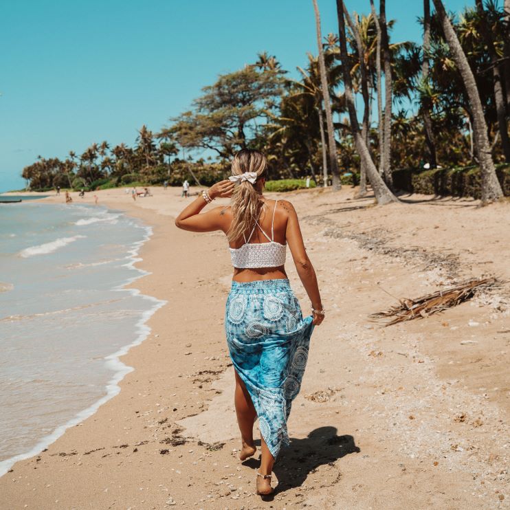 The back of a woman walking on the beach.