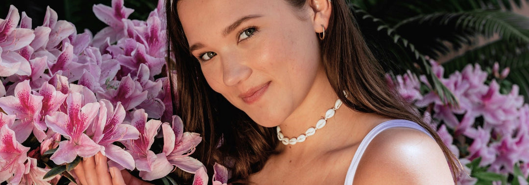 a woman's smiling face with pink flowers in the background.