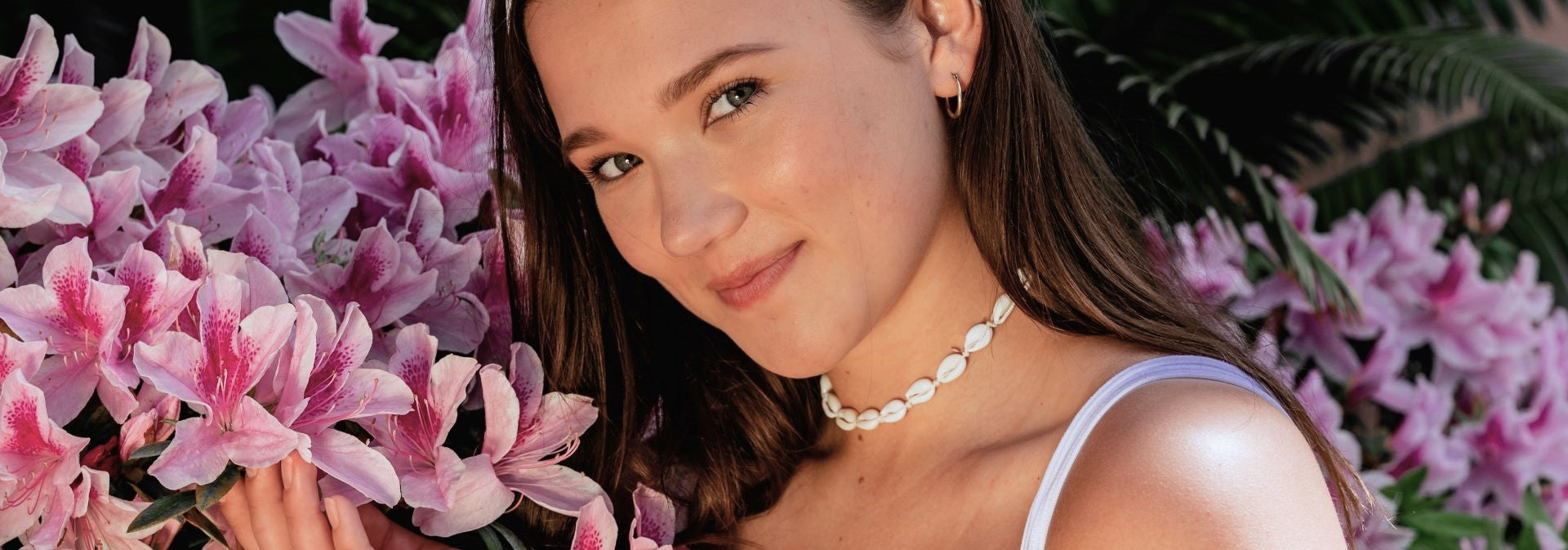 a woman's smiling face with pink flowers in the background.