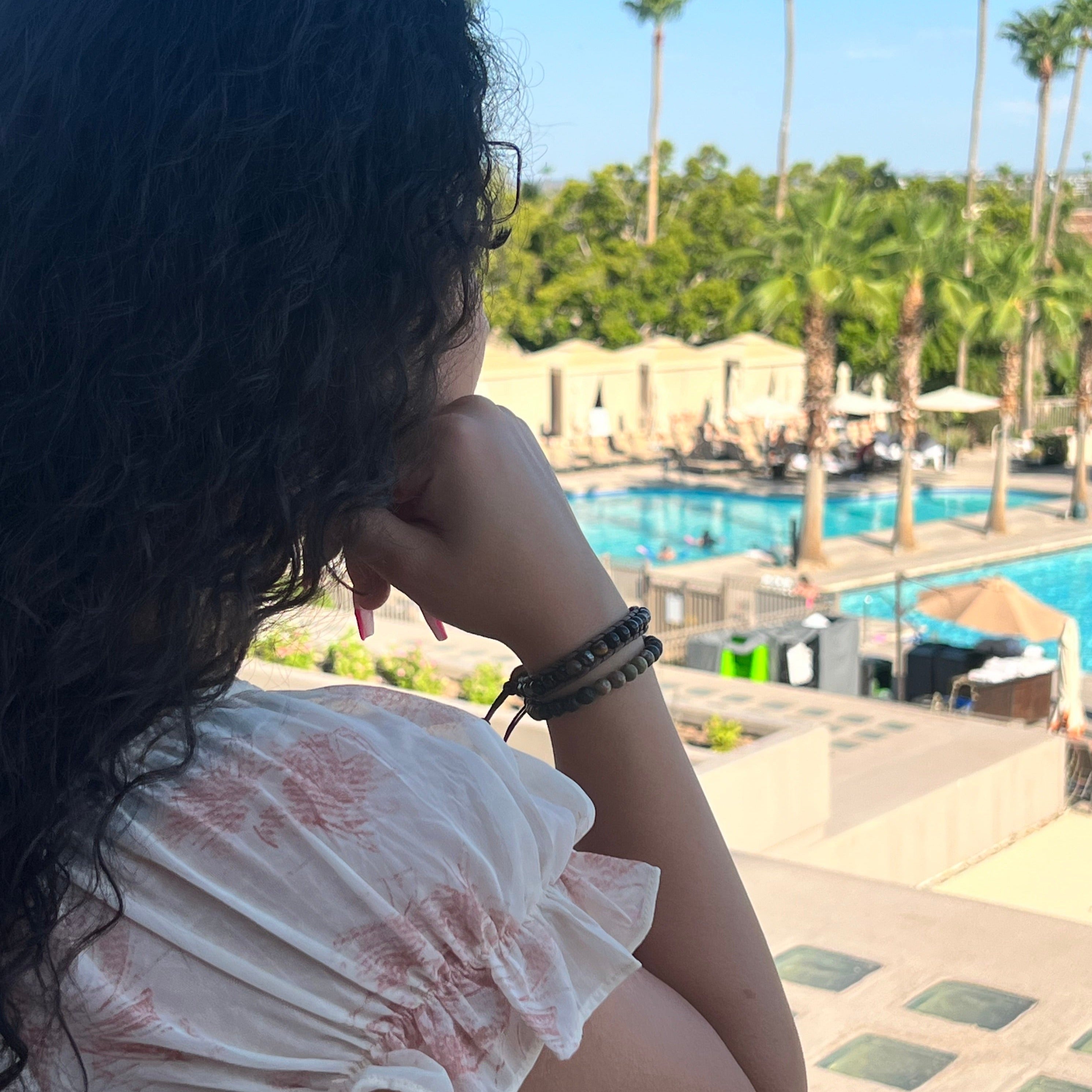 Back of a woman looking out in the distance at a pool and trees.