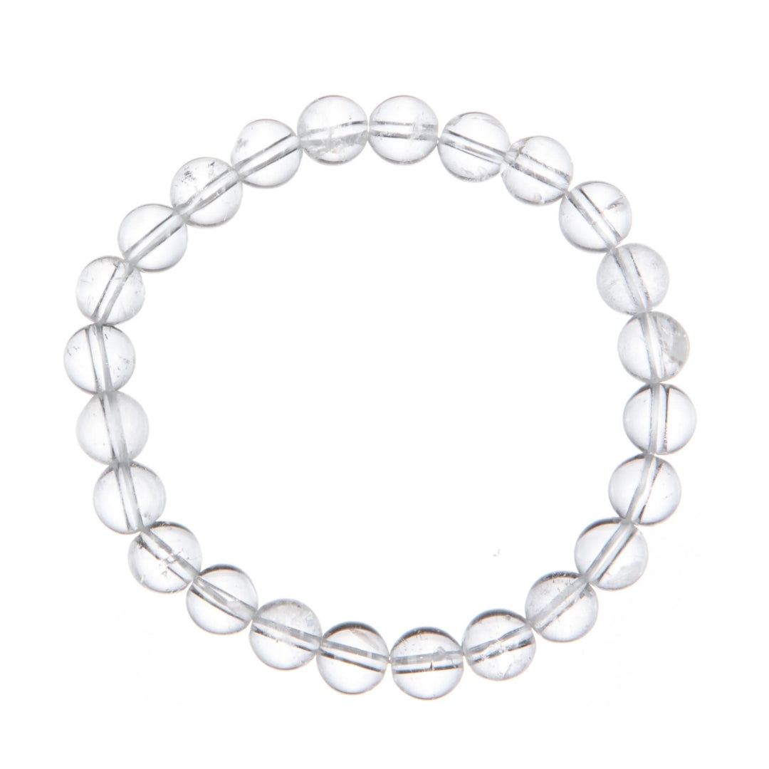 A close-up of a stretch bracelet made with 6mm round clear quartz beads connected with a clear stretch cord, on a white background.