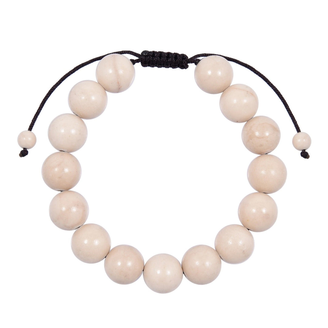 Close-up of a fossile stone bracelet made with creamy beige white 12mm round beads and a dark brown black pull tie style cord closure, displayed on a white background.