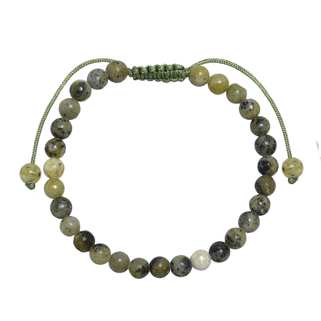 Close-up of a grass yellow turquoise bracelet made with 6mm round polished beads with shades of green yellow, and black with a green pull tie style cord closure, displayed on a white background.
