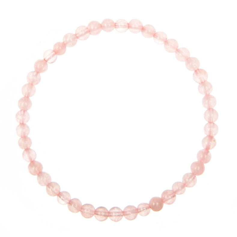 A close-up of a rose quartz stretch style bracelet made with 6mm round light pink beads, strung on a clear stretch cord, displayed on a white background.