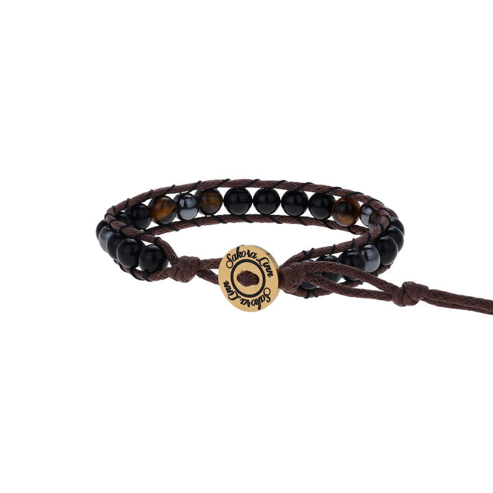 Close-up of a wrap style bead bracelet made with 6mm tiger's eye, black onyx, and hematite beads, in black, brown and dark gray colors, strung on an adjustable brown cord, with a gold logo button closure stamped in black wth Sakora Linn, displayed on a white background.
