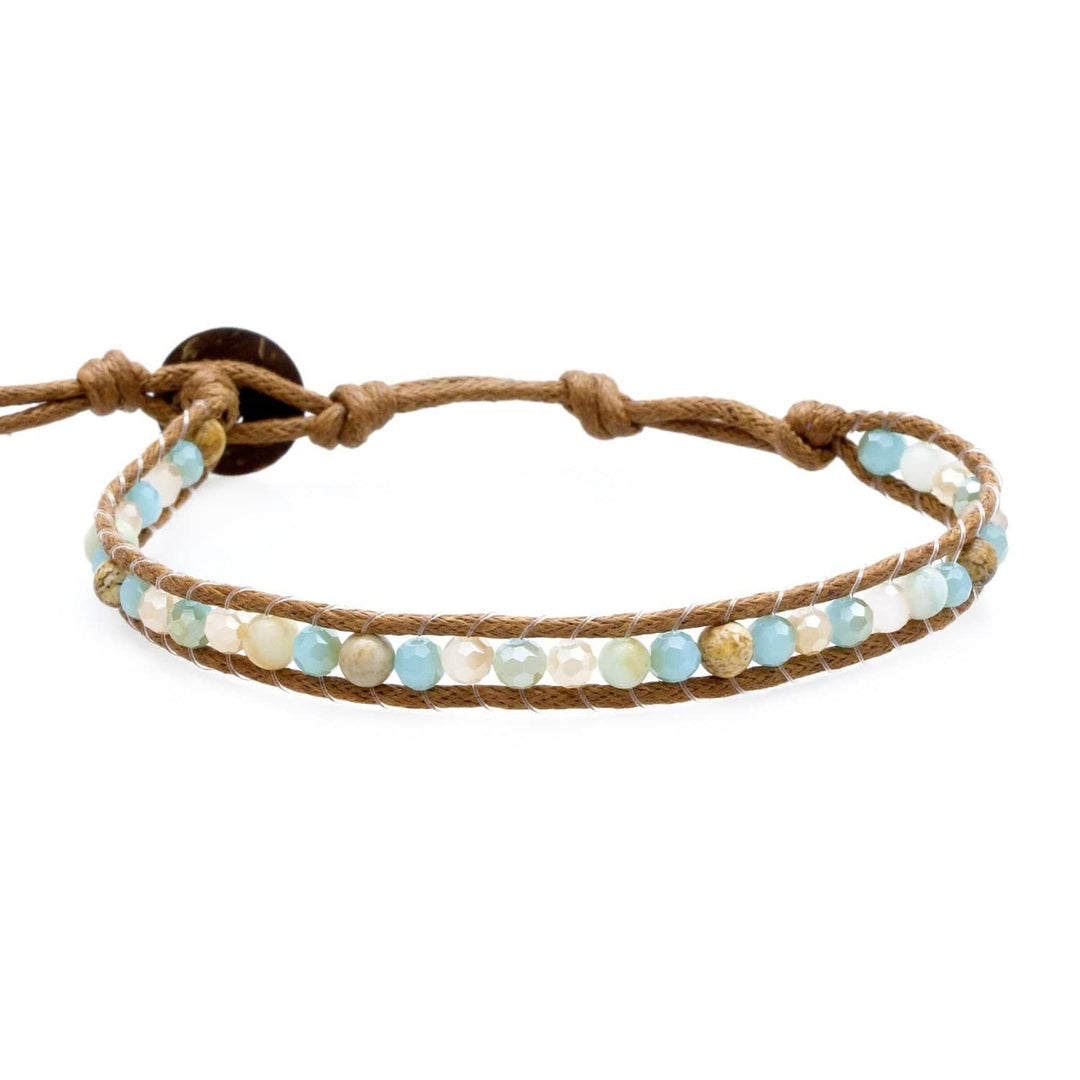 A multicolored beaded bracelet in pastel Blue, Green, Rose colors, with a brown rope-like cord, displayed on a white backgrond.