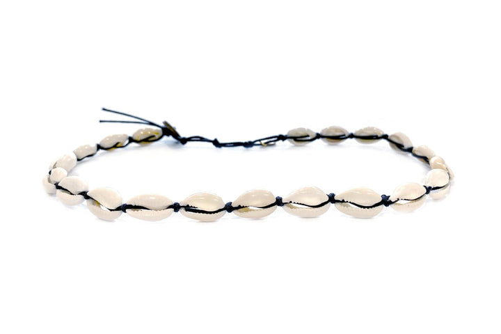 An adjustable cowry shell choker/wrap bracelet with white cowry shells and a black cotton cord, with a coconut button closure, displayed on a white background.