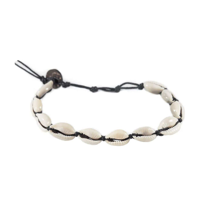 Close-up of a sea shell ankle bracelet made with white cowry sea shells, and an adustable black cord and a dark brown coconut shell button closure, displayed on a white background.