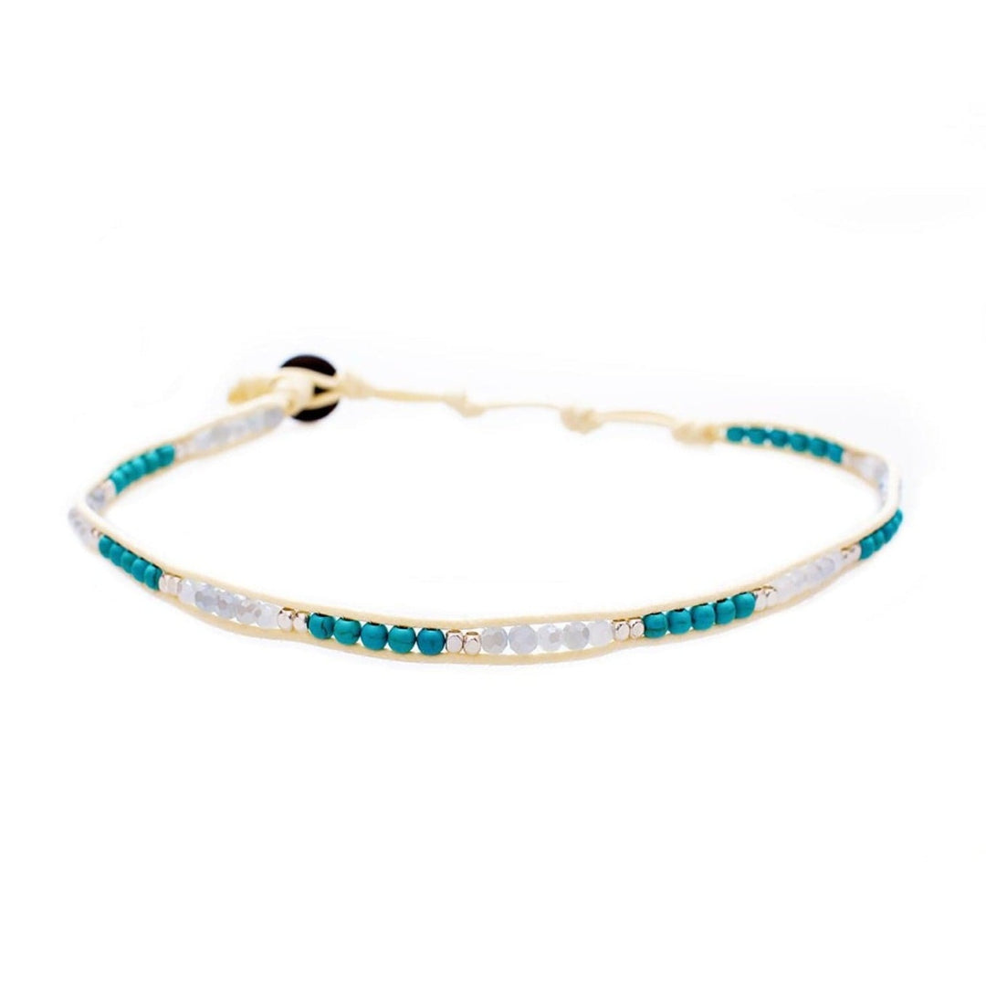 A choker necklace with turquoise magnesite beads, white crystal and silver beads, and a coconut clasp, adjustable with a cream-colored cord, displayed on a white background.
