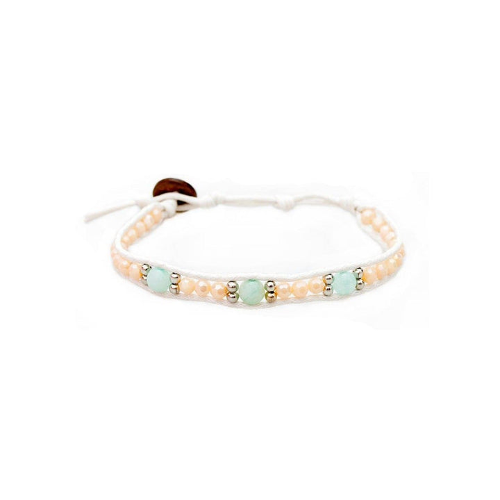 Close-up of a wrap style bracelet with three light blue amazonite beads, cream crystal beads, silver beads, a white adjustable cotton cord with a coconut button, displayed on a white background.