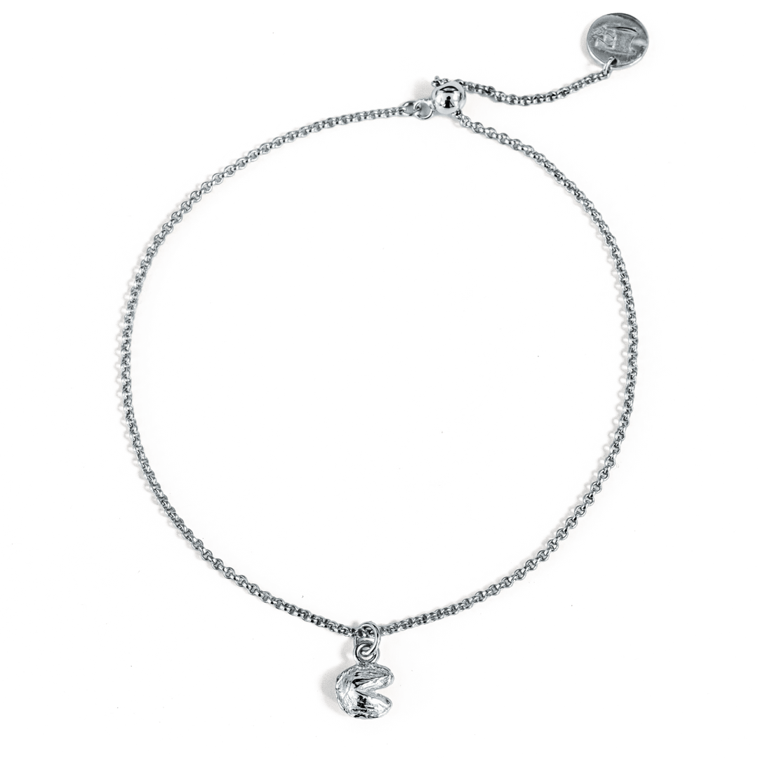 Close-up of a silver chain bracelet with a claw clasp closure, silver logo charm, and silver fortune cookie charm, displayed on a transparent background.