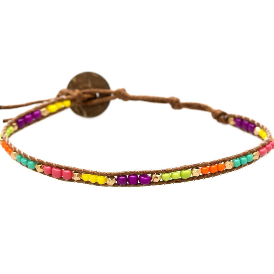 Close-up of a colorful seed bead bracelet with bright purple, yellow, orange, turquoise, green, salmon red pink, with a brown adjustabe cord and coconot button closure, on a white background.