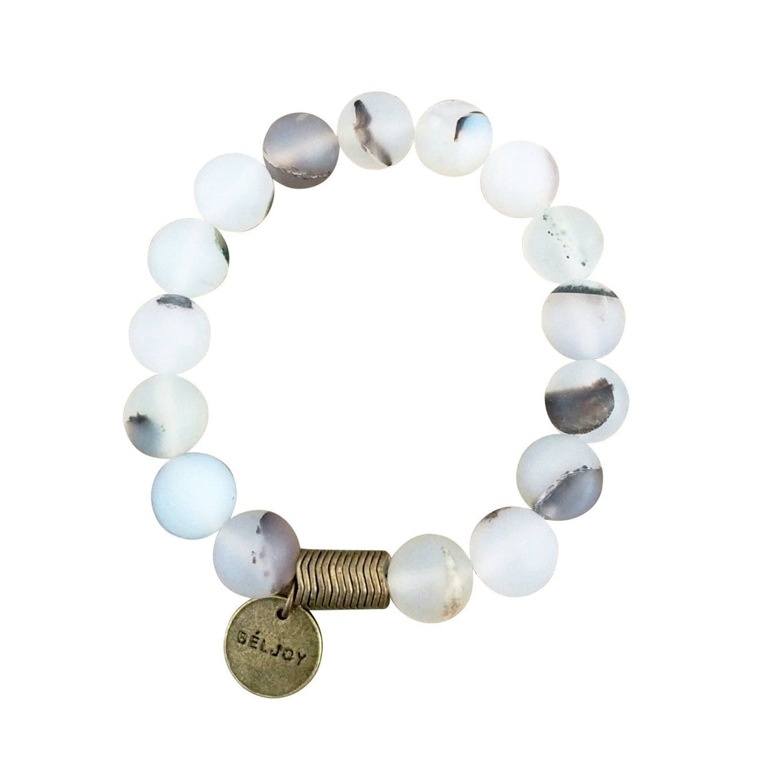 A stretch style bracelet with a mix of white and gray frosted agate beads, and a brass accent bead and logo charm, displayed on a white background.