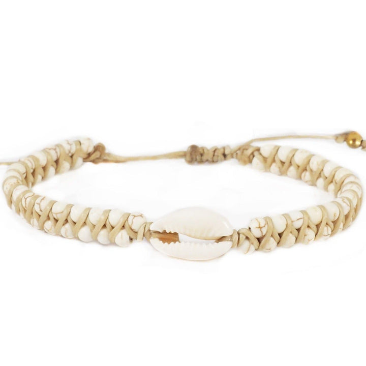 Close-up of a macrame cuff stye bracelet with white and tan marbled imitation howlite beads and a white cowry shell in the center, with a natural tan cord and slip knot closure, displayed on a white background.