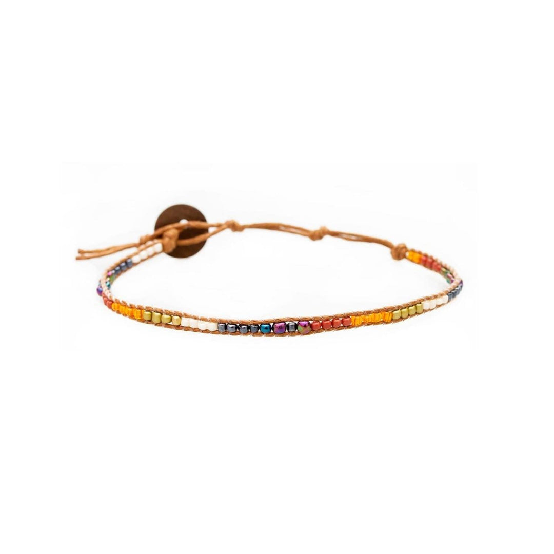 Close-up of a seed bead wrap bracelet with white, red, blue, and orange beads, a brown adjustable cord and coconut btton closure, displayed on a white background.