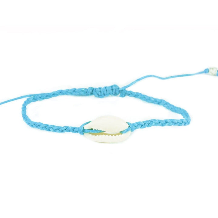 Close-up of a blue braided slip knot syle bracelet with a white cowry sea shell in the center, displayed on a white background.