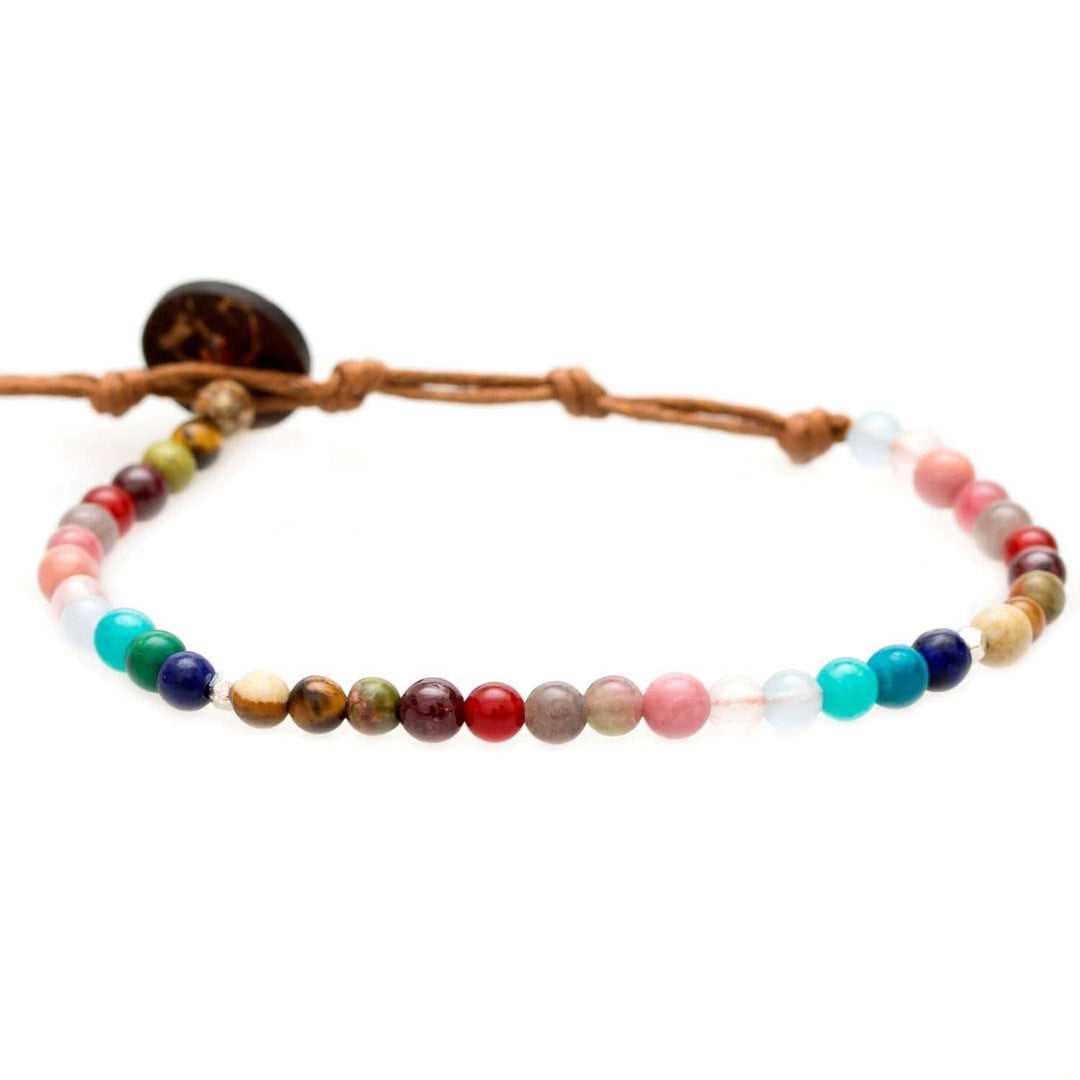 Close-up of a bead bracelet made with 4mm multicolor round jade, amazonite, quartz, tiger's eye, garnet, and unakite beads, in pink, red, teal, blue, brown, orange, green, purple colors, with a brown adjustable cord and a dark brown coconut shell button closure, displayed on a white background.