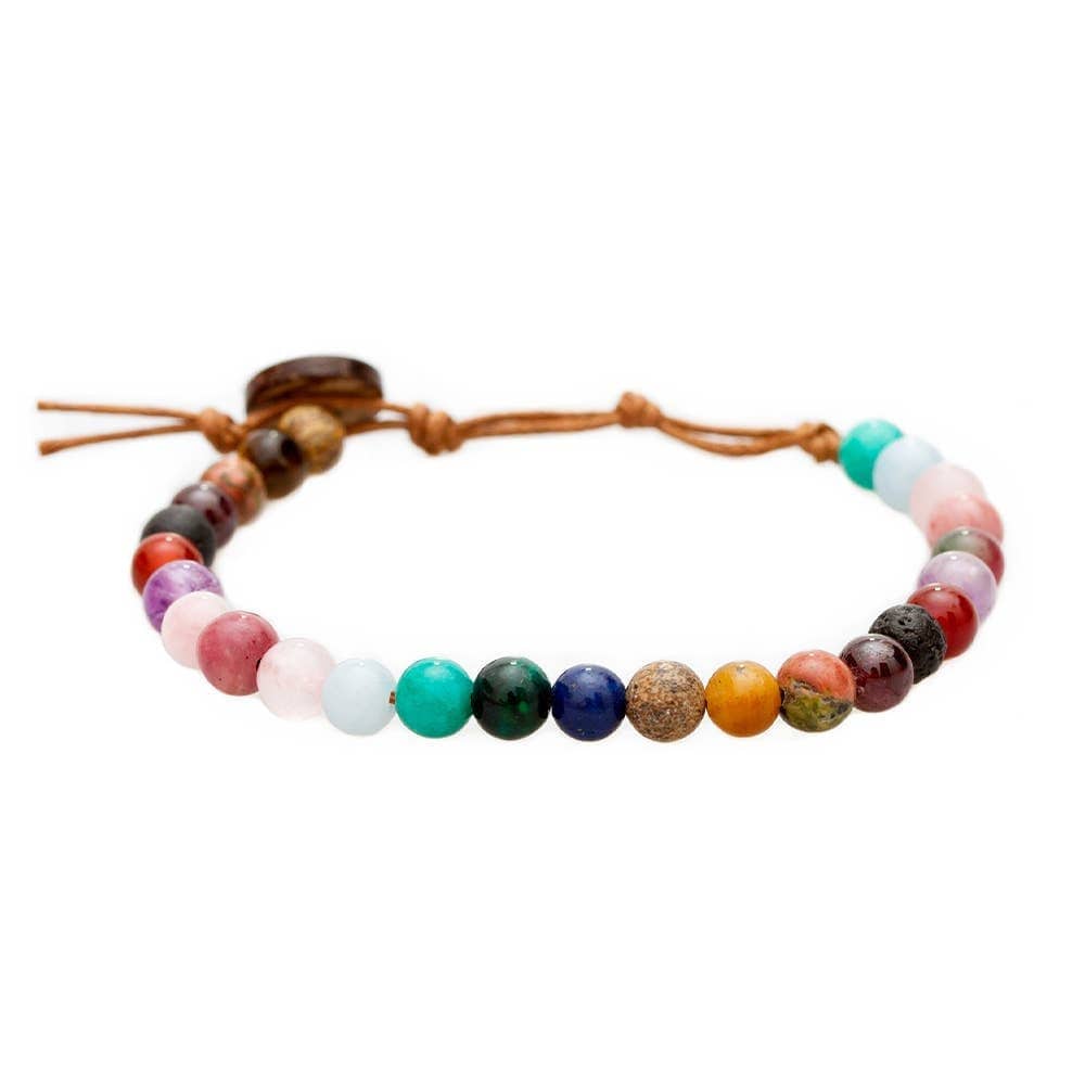 Close-up of a healing bead bracelet with round 6mm jade, jasper, amazonite, quartz, tiger's eye, garnet, and unakite beads in pink, red, teal, brown, green, purple, and tan colors, with a adjustable brown cord and dark brown coconut shell button closure, displayed on a white background.