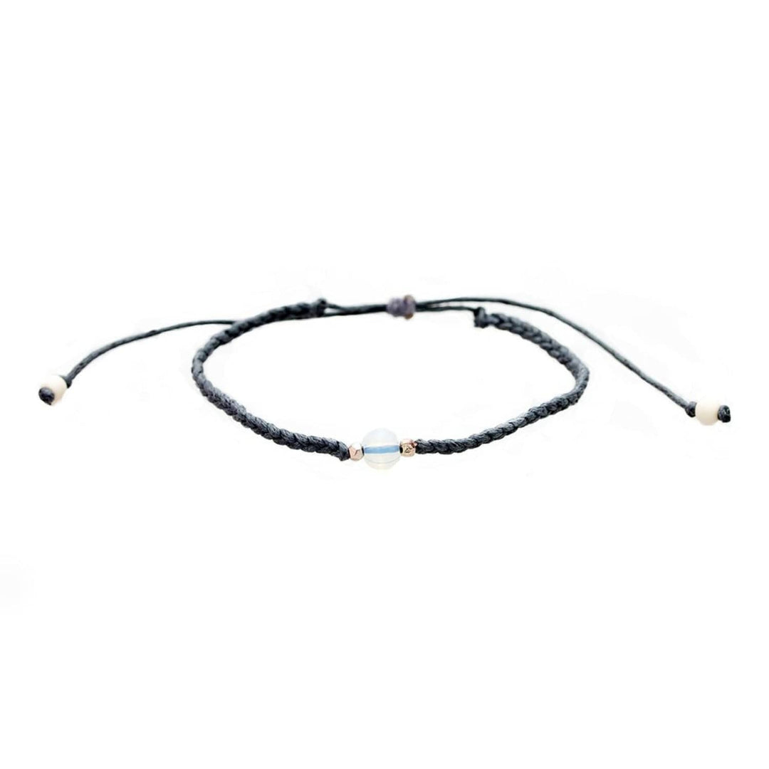 Close-up of a gray braided slip knot syle bracelet with a moonstone in the center and small gold accent beads on each side of the moonstone, displayed on a white background.