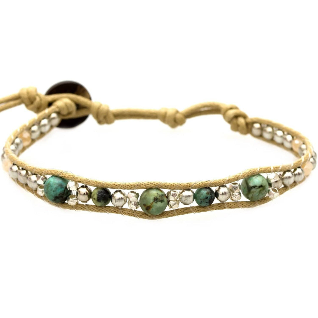 Close-up of a beaded wrap bracelet with three green turquoise beads and smaller silver beads, on an adjustable tan cord with a coconut shell button closure, displayed on a white background.