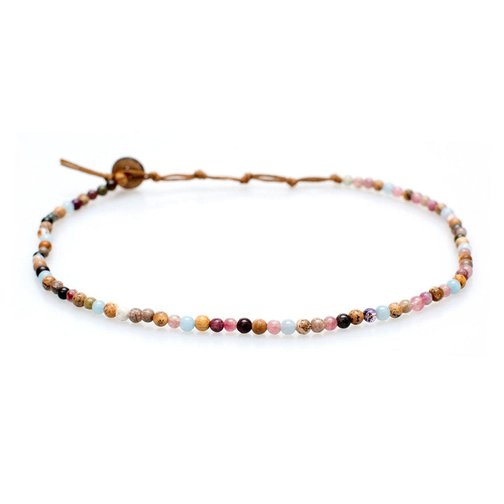 Close-up of a beaded necklace with 4mm Jasper and Tourmaline stone beads in shades of brown, pink, blue, deep purple, with tan cord and coconut button closure, displayed on a white background.