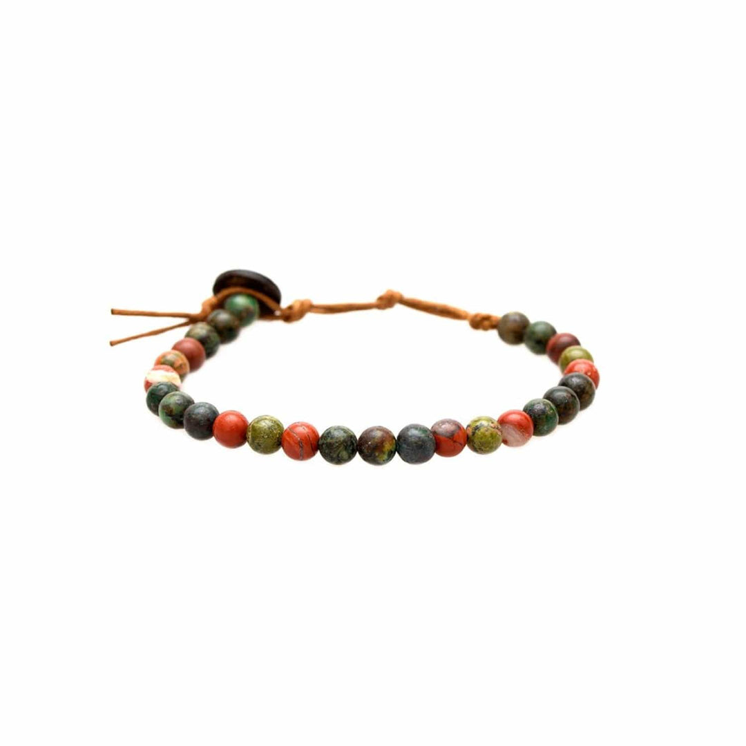 Close-up of a healing bead bracelet with round 6mm jasper, unakite, and african turquoise beads in shades of brown, green, and red colors, with an adjustable brown cord and dark brown coconut shell button closure, displayed on a white background.