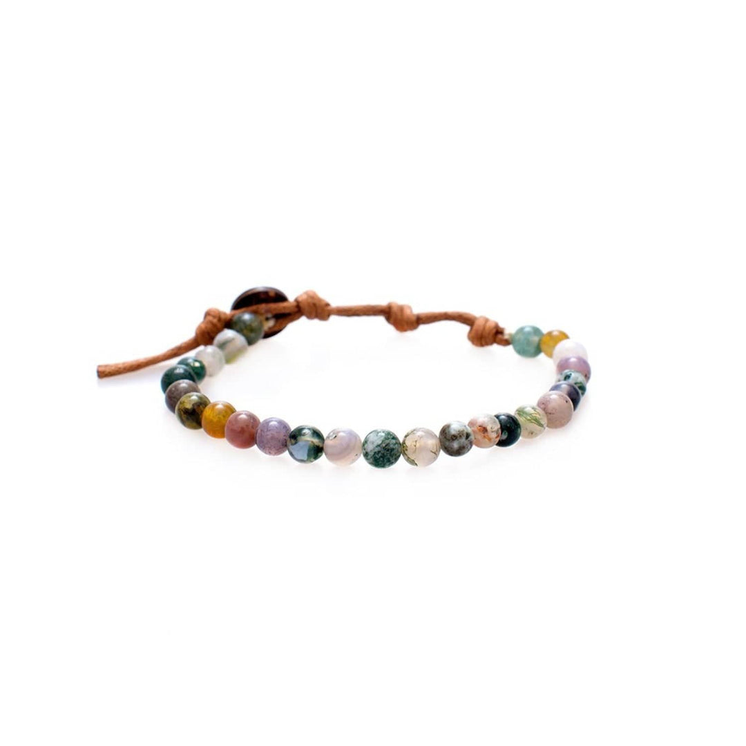 Close-up of a healing bead bracelet with round 6mm jade and other stone beads in shades of  green, tan, and clear colors, with a adjustable brown cord and dark brown coconut shell button closure, displayed on a white background.