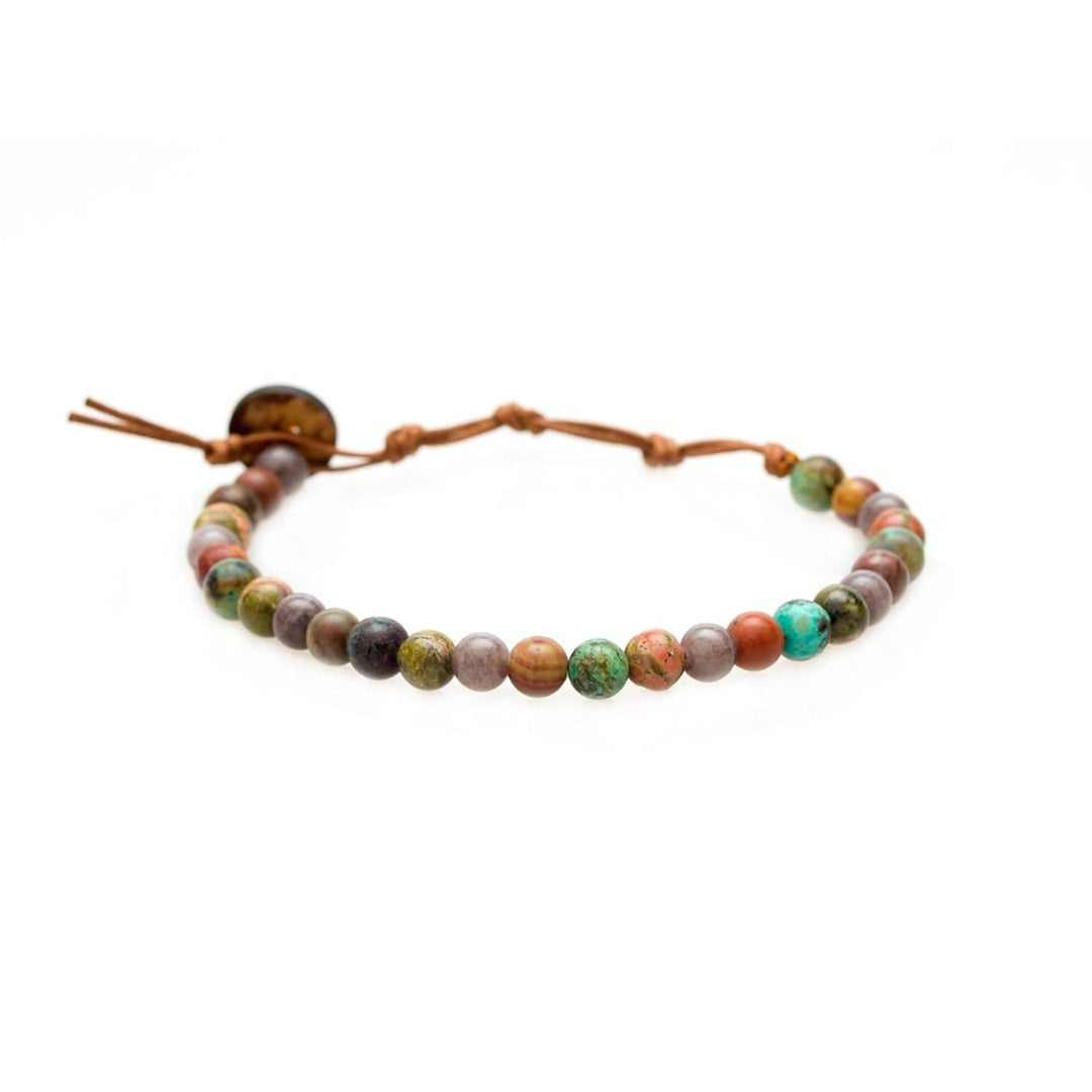 Close-up of a healing bead bracelet with round 6mm african turquoise and quartz beads in shades of brown, green, teal and tan colors, with a adjustable brown cord and dark brown coconut shell button closure, displayed on a white background.