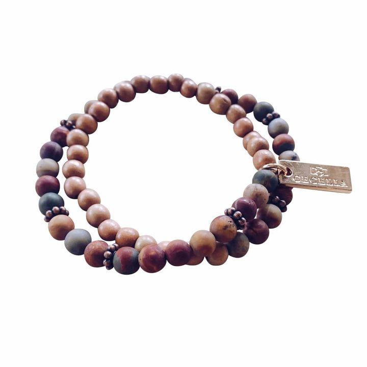 A stretch syle double-wrap bracelet made with red creek jasper beads with shades of deep red, gray, tan, and brown wood, beads with copper accent beads, and a gold-tone logo tag, displayed on a white background.