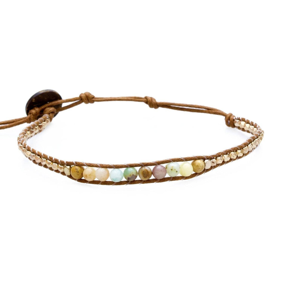 Close-up of a beaded wrap bracelet with amazonite, jasper, and gold tone beads, in shades of green, mauve, blue, yellow, on an adjustable tan cord with a coconut shell button closure, displayed on a white background.