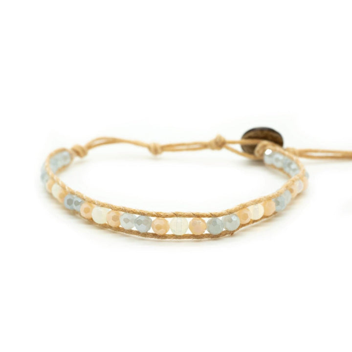 Close-up of a beaded wrap bracelet with pastel colored amazonite crystals in blue, orange, and pink, with an adjustable tan cord and coconut button closure, displayed on a white bakground.