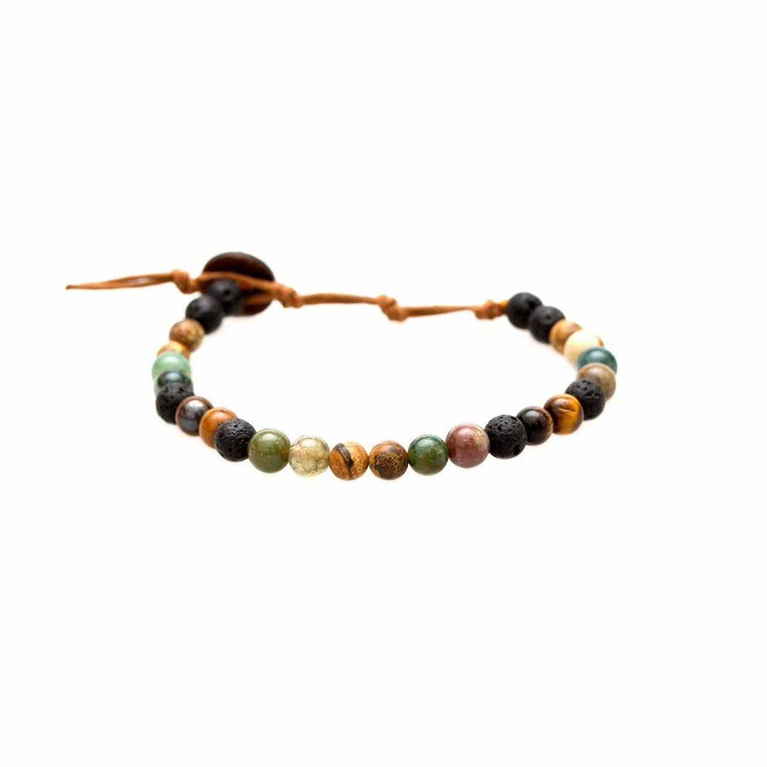 Close-up of a healing bead bracelet with round 6mm lava stone and tiger's eye beads in shades of brown and green, and black colors, with a adjustable brown cord and dark brown coconut shell button closure, displayed on a white background.
