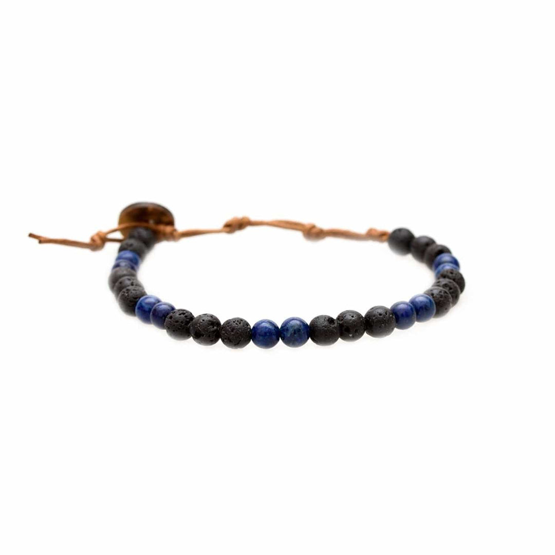 Close-up of a healing bead bracelet with round 6mm lava stone and lapis lazuli beads in black and blue colors, with a adjustable brown cord and dark brown coconut shell button closure, displayed on a white background.