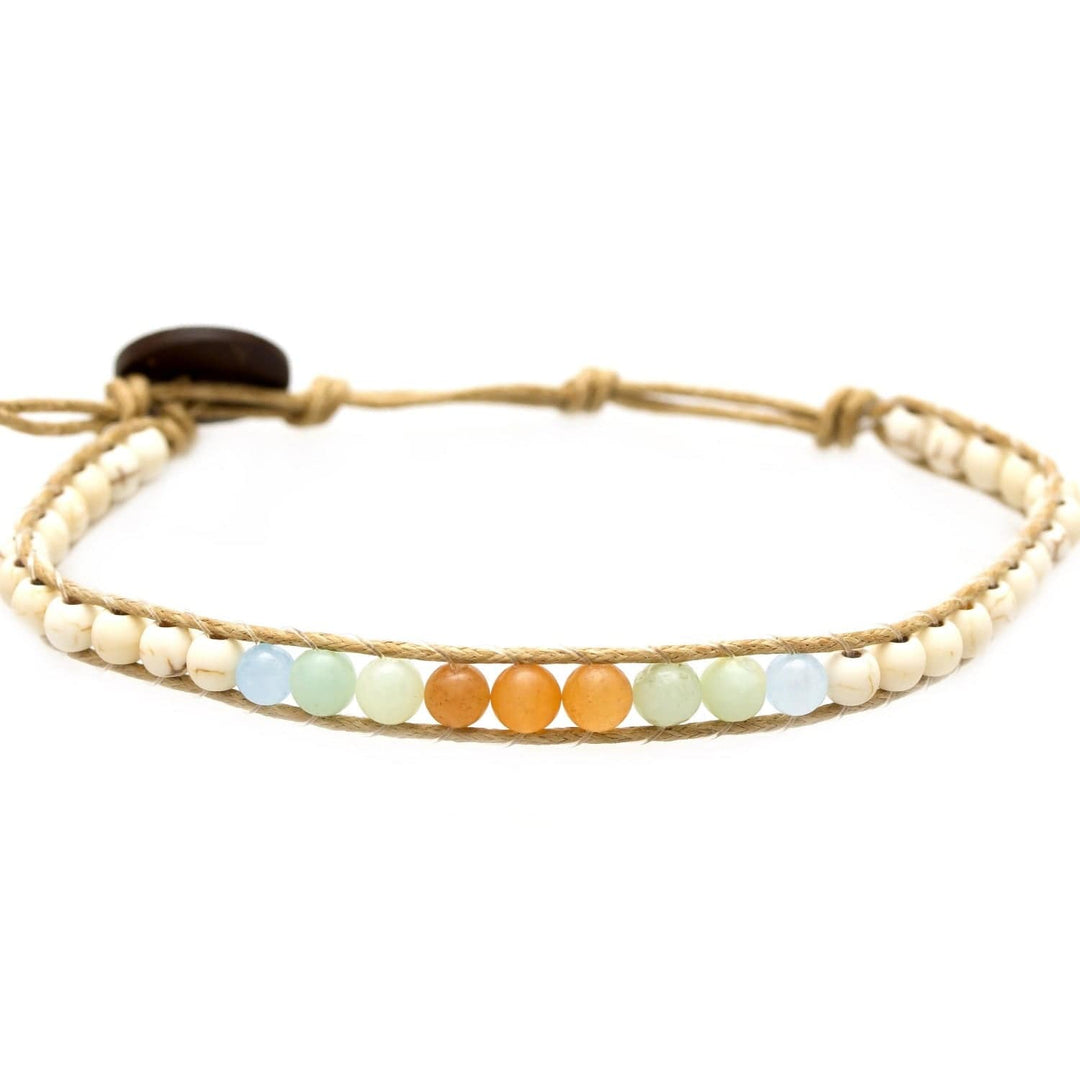 Close-up of a beaded wrap bracelet with amazonite, howlite, and agate beads in pastel shades of orange, blue, green, white and tan, on an adjustable tan cord with a coconut shell button closure, displayed on a white background.