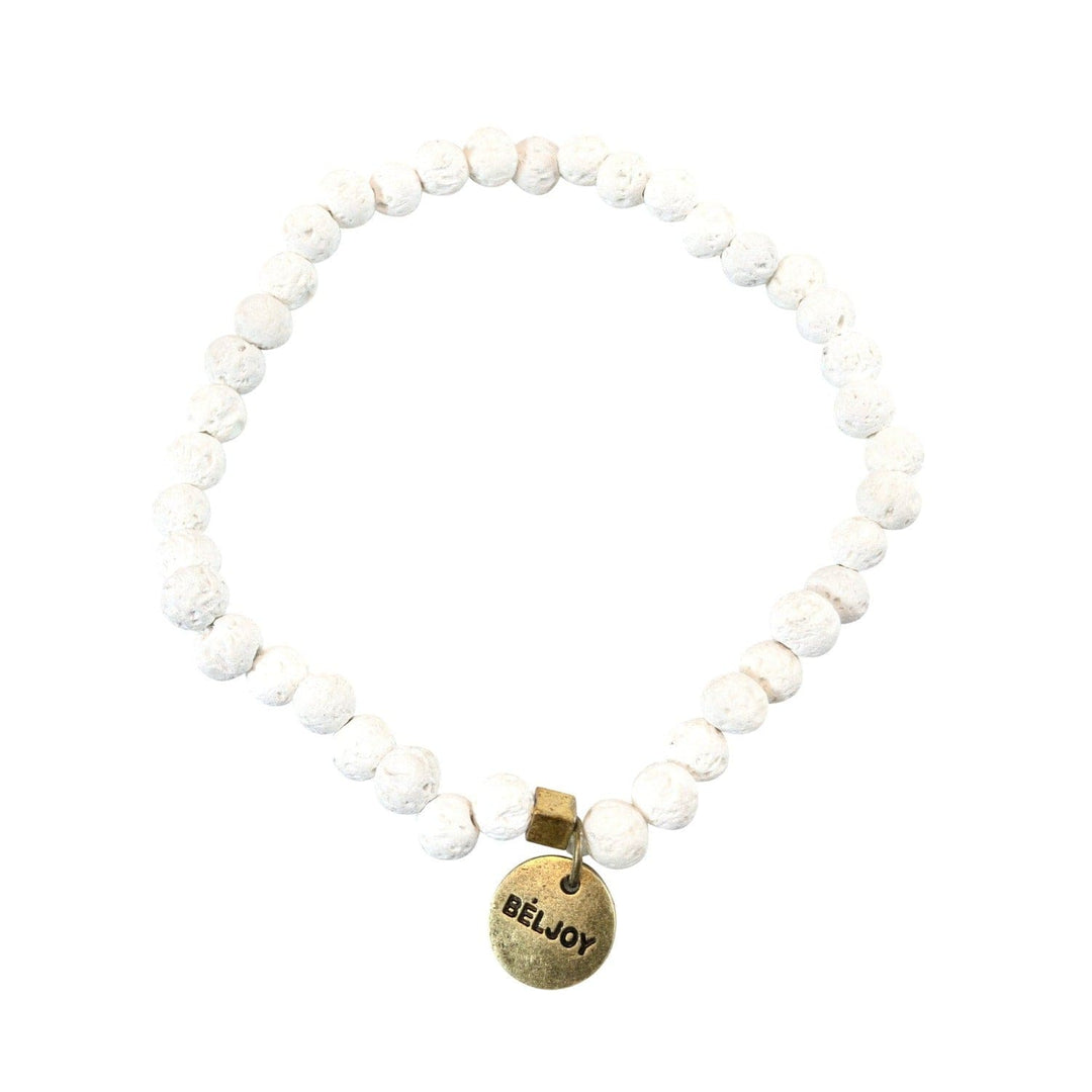 A stretch style white lava stone bead bracelet with 4mm round beads, a square gold brass bead accent, and a gold brass beljoy logo charm, displayed on a white background.